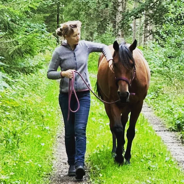 Nicole Albers führt ein Pferd über einen Waldweg