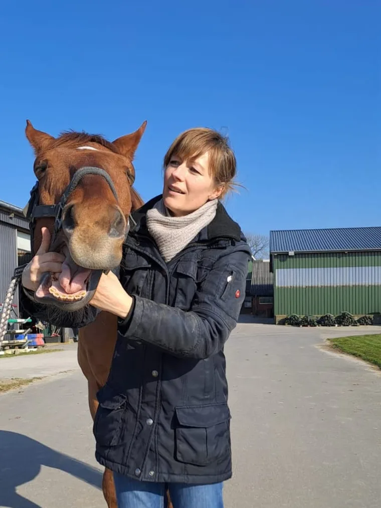 Nicole Albers hält lachend den Kopf eines Fuchses vor klarem blauem Himmel